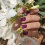 VIOLET VOUGE UV Gelnailz. Gepflegte Fingernägel, die eine weiße Blume umschließen