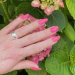 Lange Nägel mit PINK neon Nailz bei Tageslicht vor blumigem Hintergrund