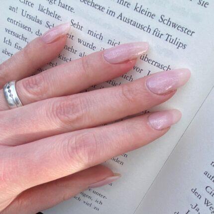 BABY pink UV Gelnailz. Schöne lange Fingernägel im zarten Pinkton auf einem geöffneten Buch