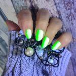 Leuchtende GREEN neon Nailz mit Brosche in der Hand bei UV Licht