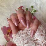 Schimmernde LIGHT PINK glitter Nailz in zartem Rosa, vor einem hellen Hintergrund mit Blumen.