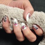 Aufgeklebte MINNIE CRUSH Nailz auf Fingern, dekorativ mit beigem Stoff in der Hand